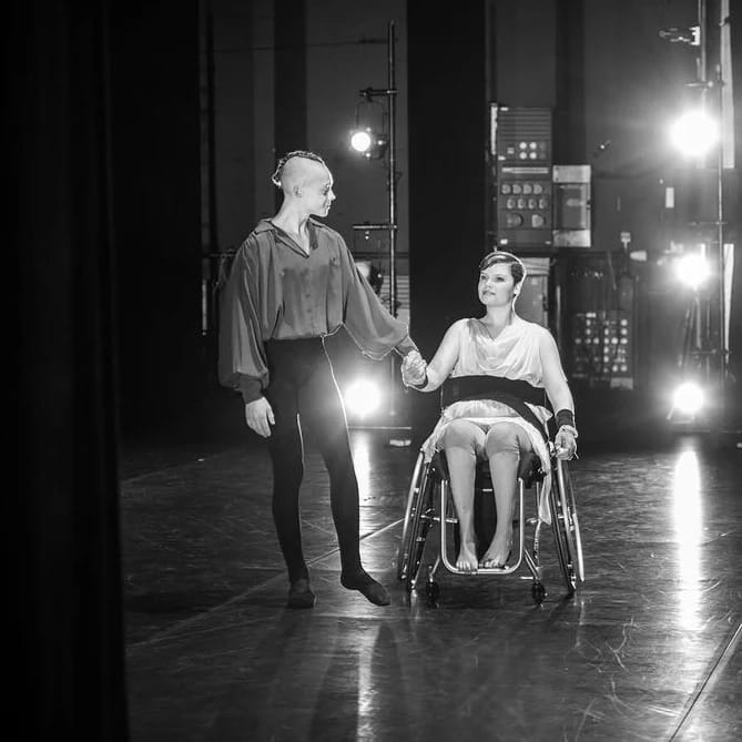 A black and white photo of Grace in a wheelchair with another male performer